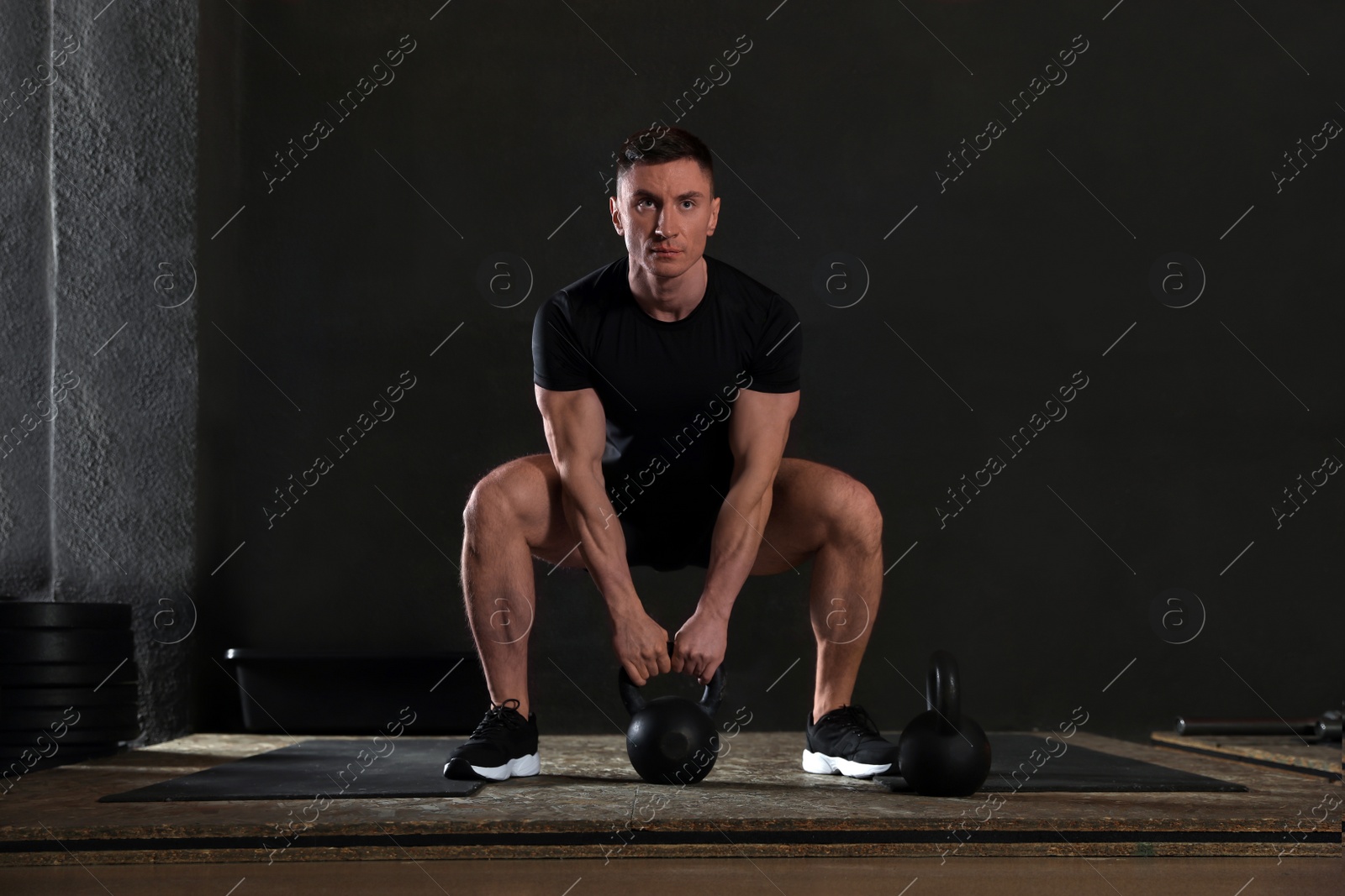 Photo of Strong man working out with kettlebell in modern gym
