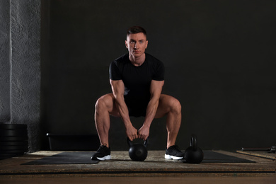 Photo of Strong man working out with kettlebell in modern gym