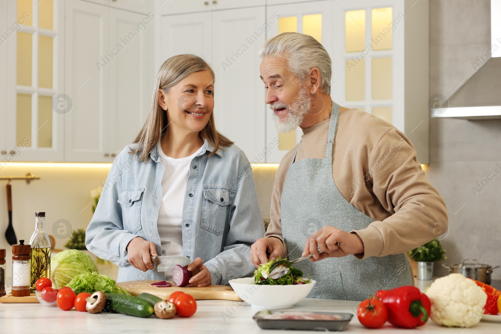 Photo of Happy senior couple cooking together in kitchen