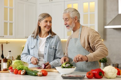 Photo of Happy senior couple cooking together in kitchen