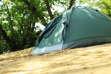 Photo of Modern camping tent in forest. Space for text