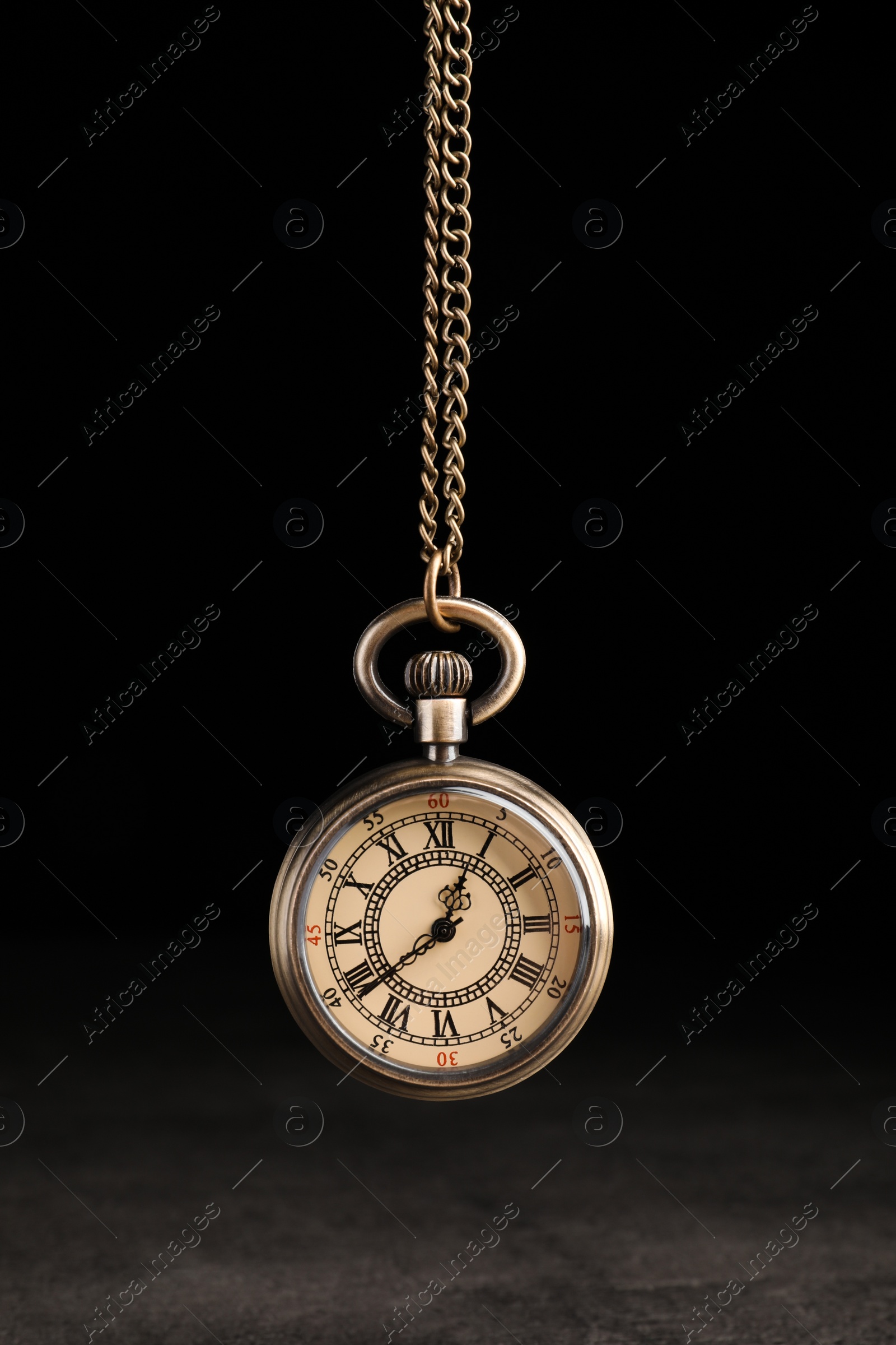 Photo of Stylish pendulum above table on black background. Hypnotherapy session