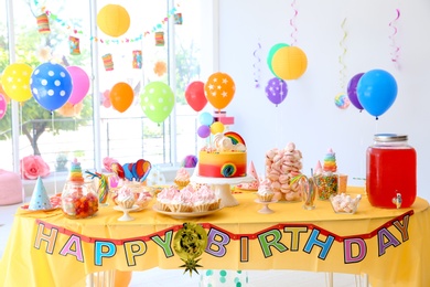 Table with birthday cake and delicious treats indoors