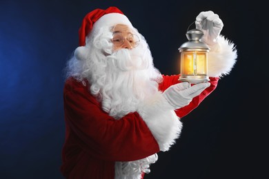 Photo of Santa Claus with Christmas lantern on dark blue background
