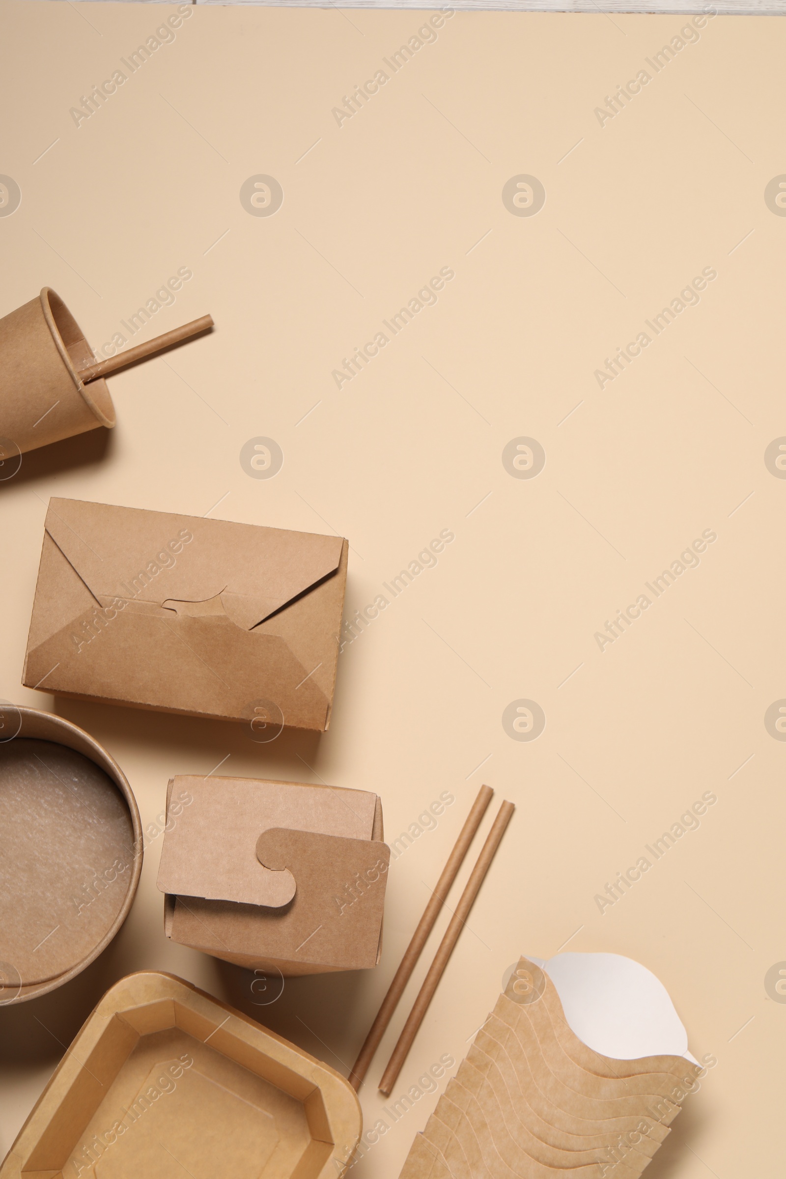 Photo of Eco friendly food packaging. Different paper containers on beige background, flat lay. Space for text