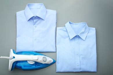 Photo of Folded clean clothes and iron on color background, top view