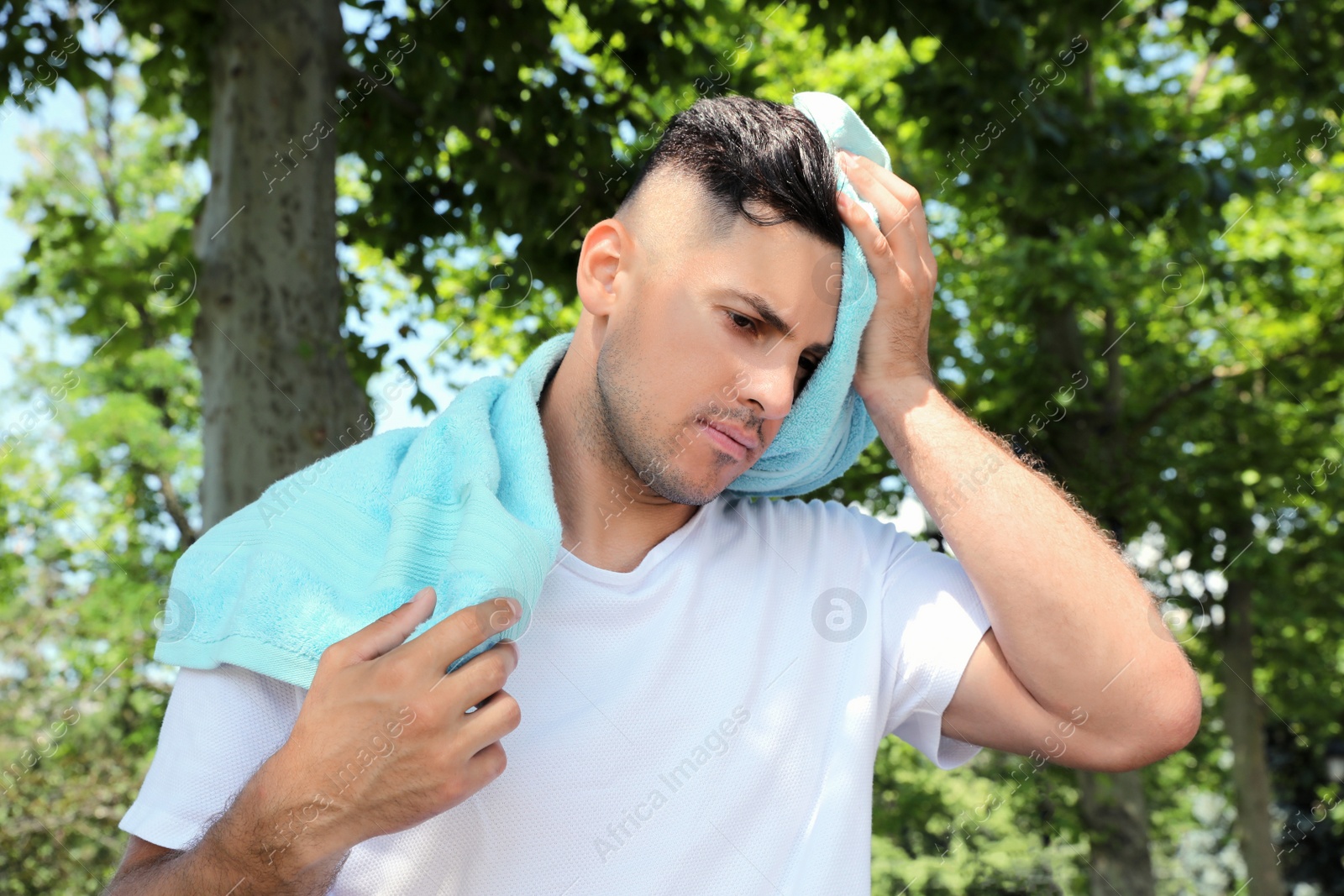 Photo of Man with towel suffering from heat stroke outdoors