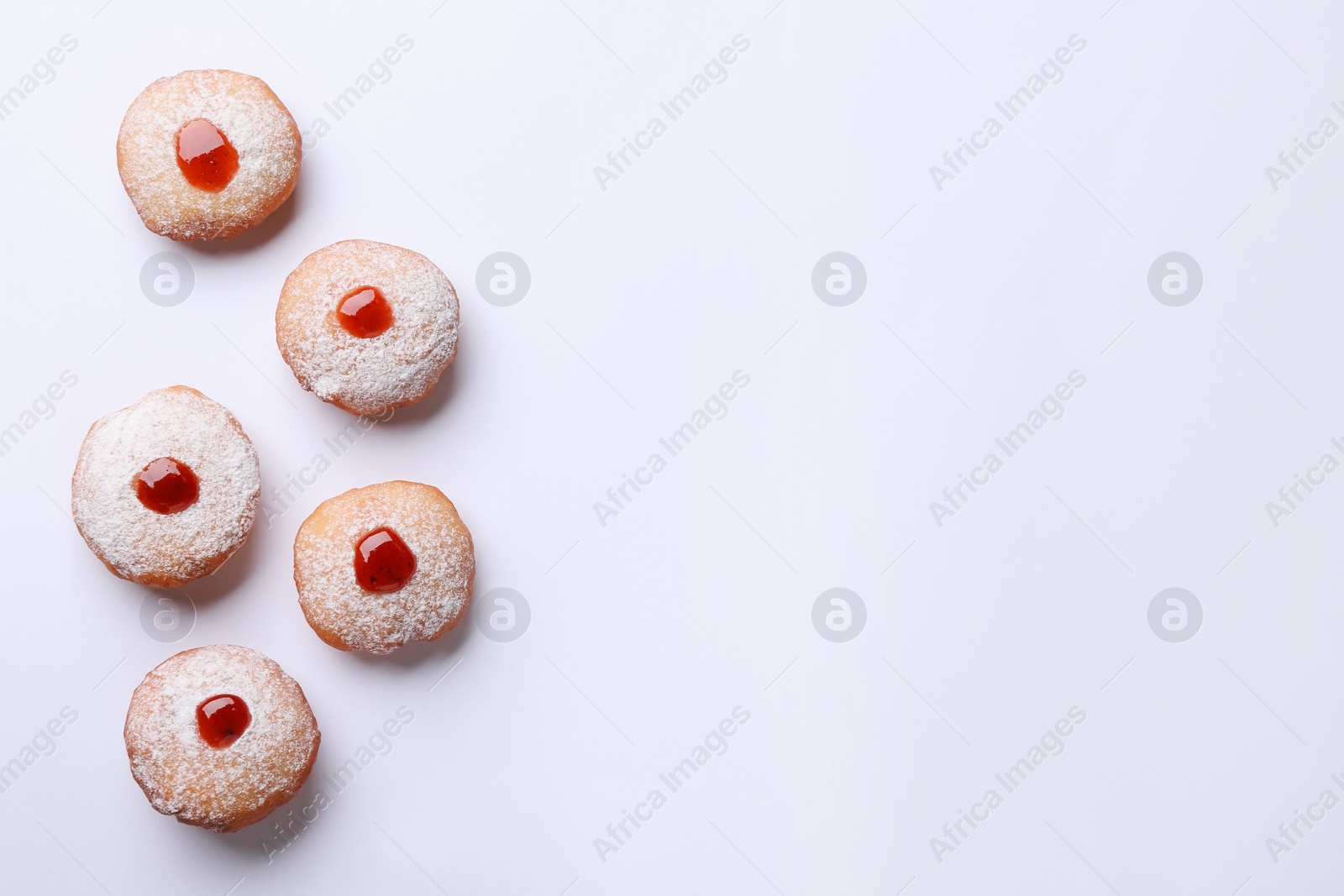 Photo of Hanukkah donuts with jelly and powdered sugar on white background, flat lay. Space for text