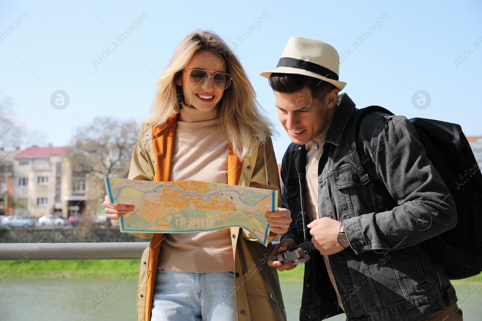 Photo of Couple of tourists with map on city street near beautiful river