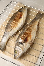 Photo of Baked fish on light marble table, closeup