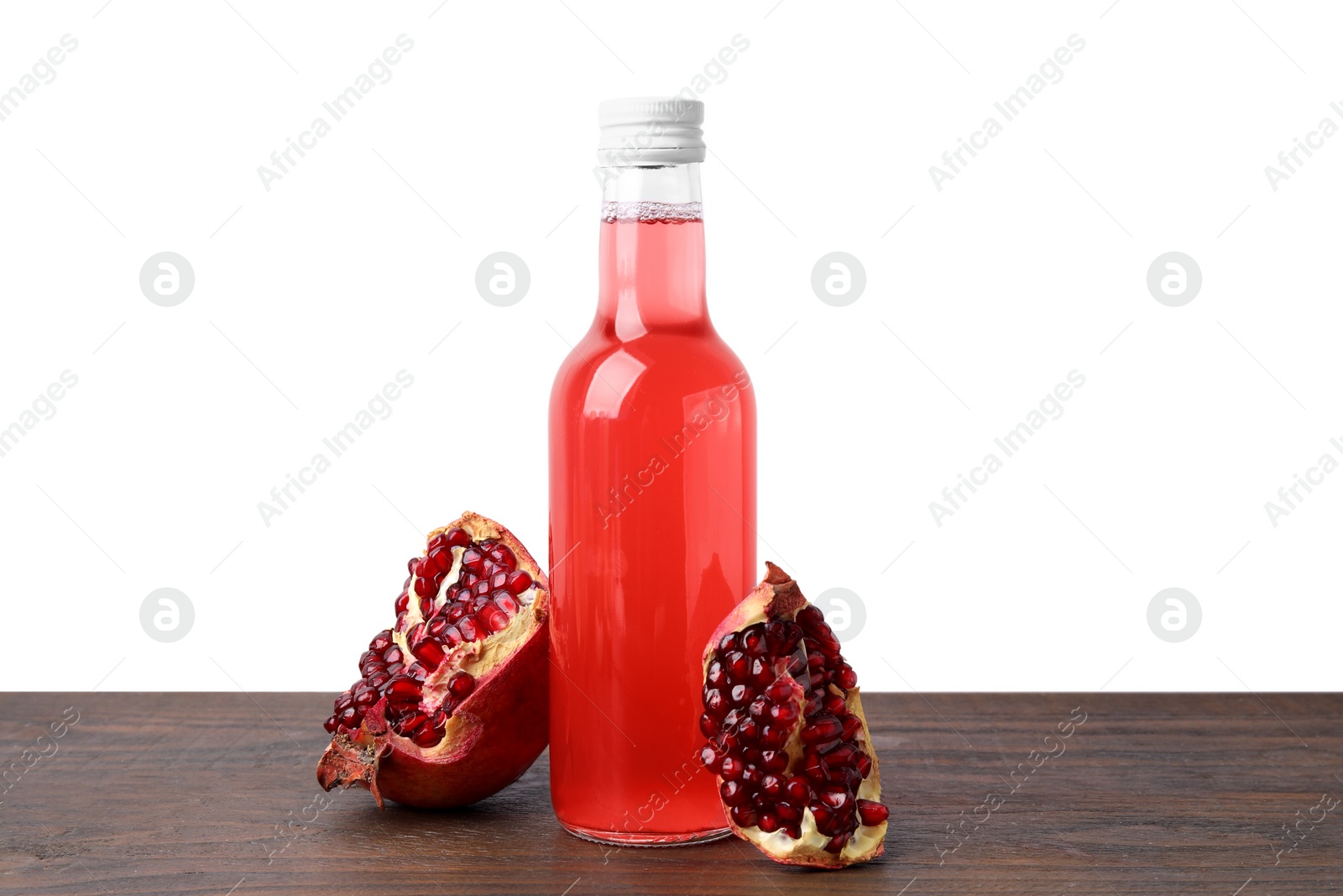 Photo of Delicious kombucha in glass bottle and pomegranate on wooden table against white background