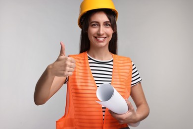 Photo of Architect in hard hat with draft showing thumbs up on light grey background