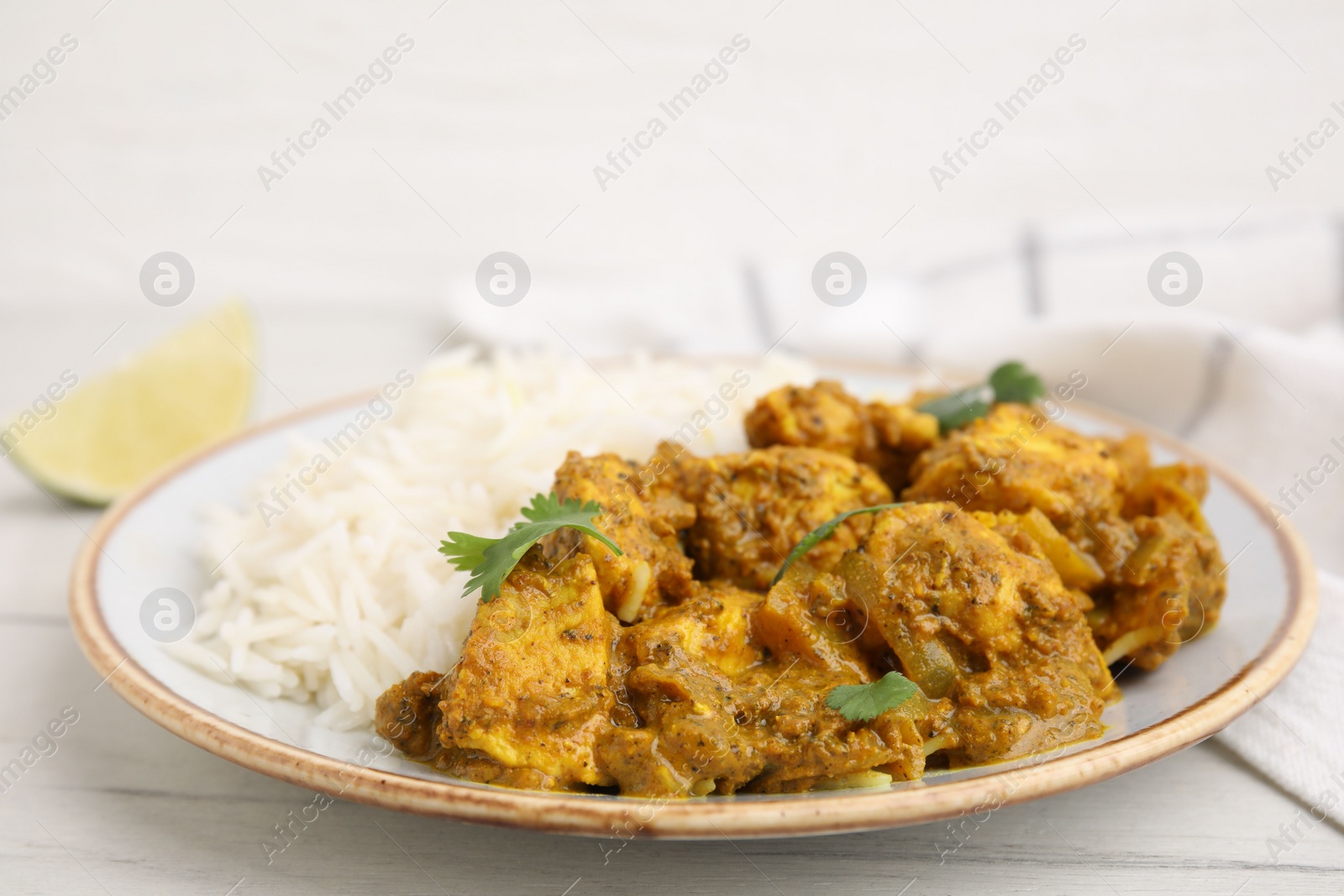 Photo of Delicious chicken curry with rice on white wooden table