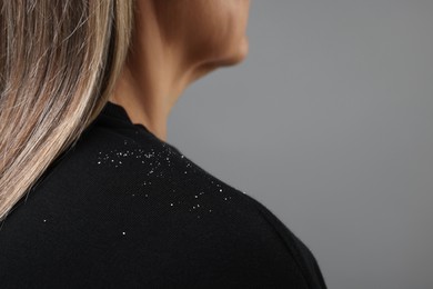 Photo of Woman with dandruff on her sweater against gray background, closeup. Space for text
