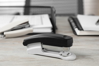 Photo of Stapler on wooden table, closeup. Office stationery