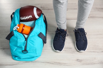 Photo of Young man in sportswear and bag with gym equipment indoors