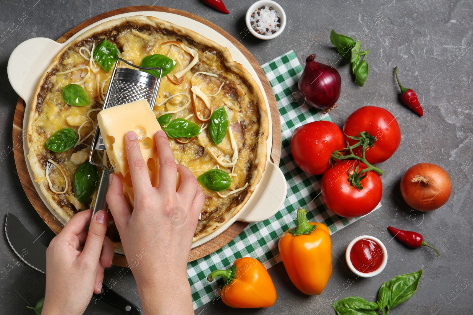 Photo of Woman grating cheese onto delicious homemade pizza at table, top view