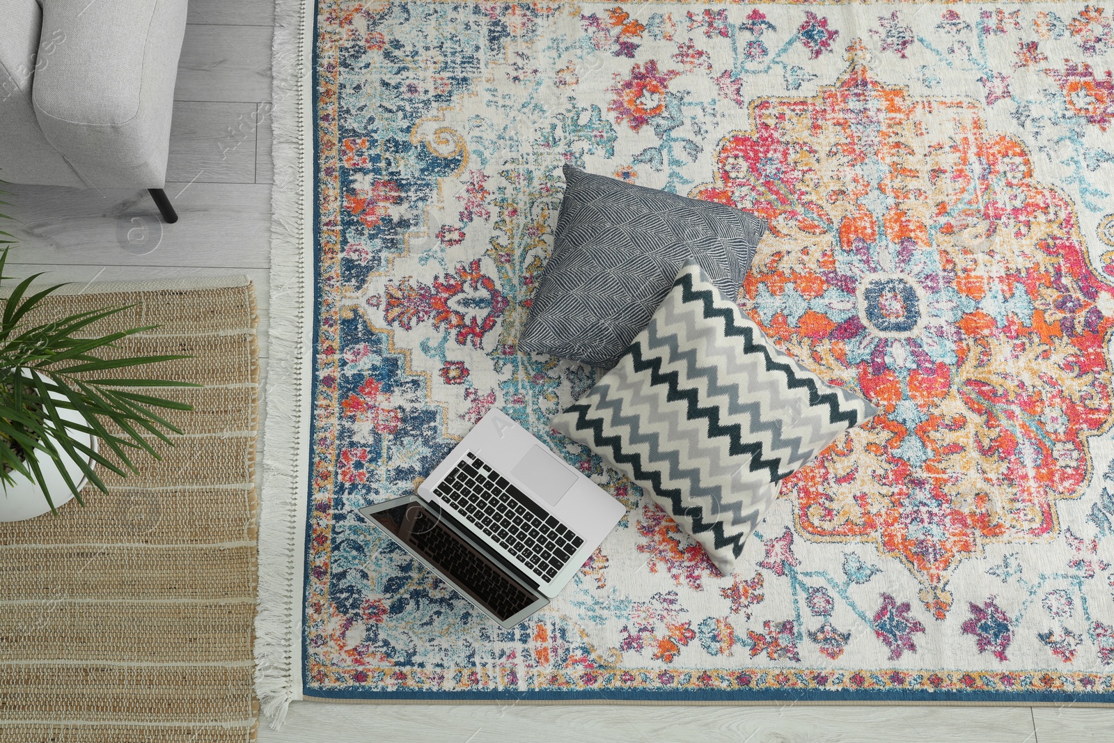 Photo of Stylish living room with beautiful carpet, laptop and pillows on floor, above view. Interior design