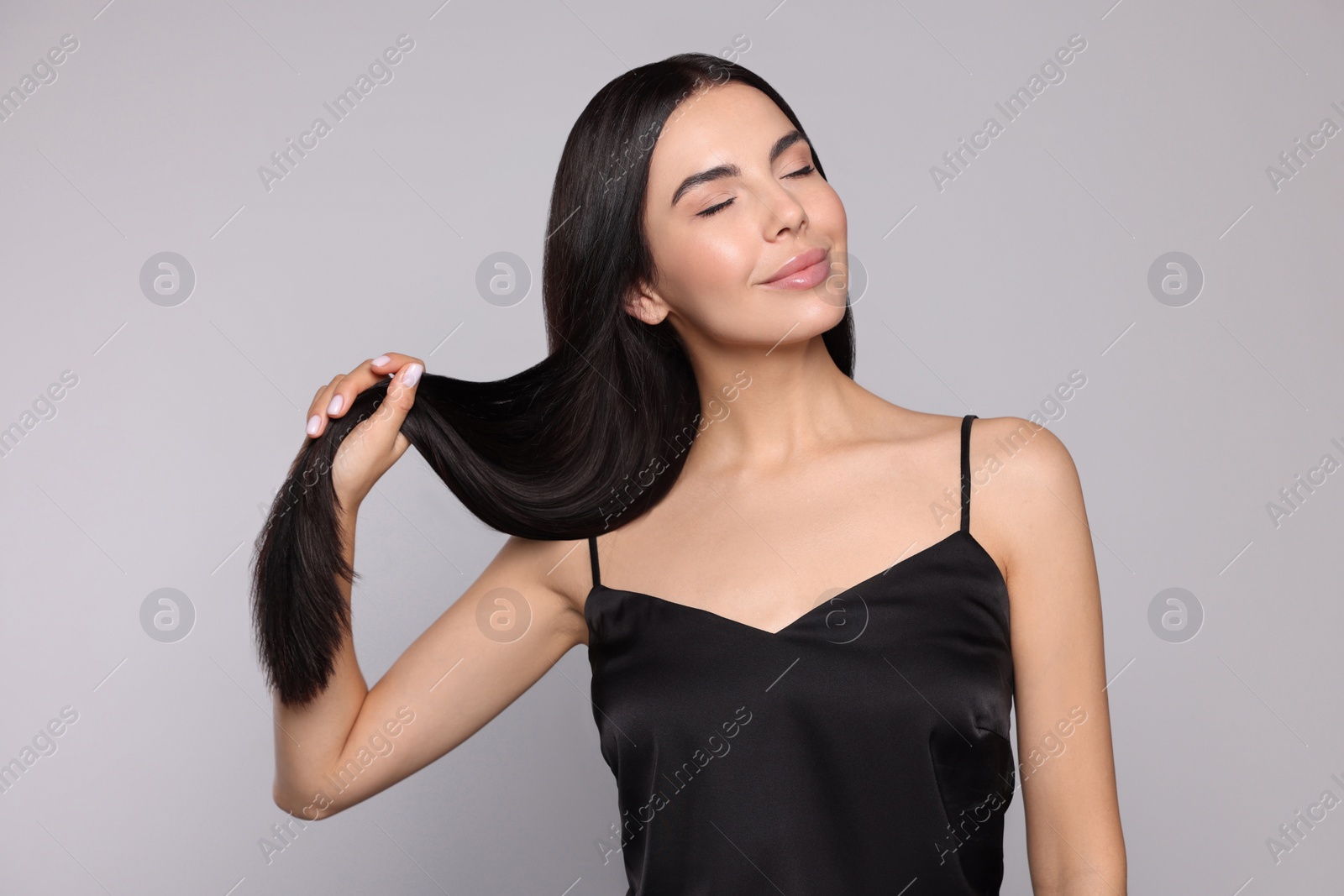 Photo of Portrait of beautiful young woman with healthy strong hair on light grey background