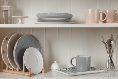 Photo of Stylish storage stand with different ceramic dishware at home