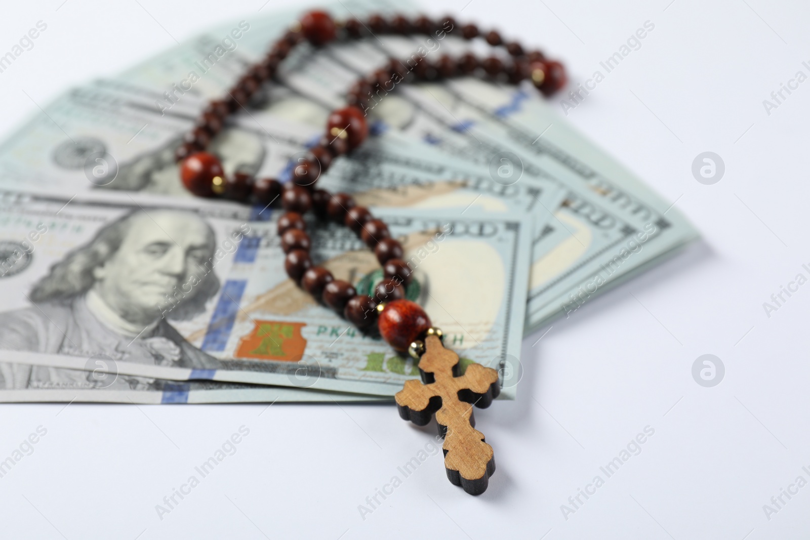 Photo of Wooden cross and money on white background, closeup