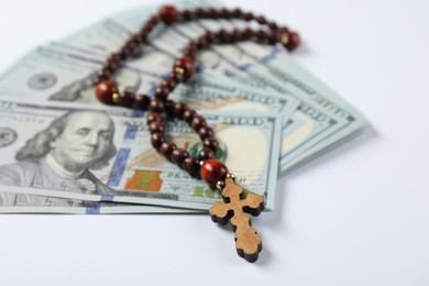 Wooden cross and money on white background, closeup