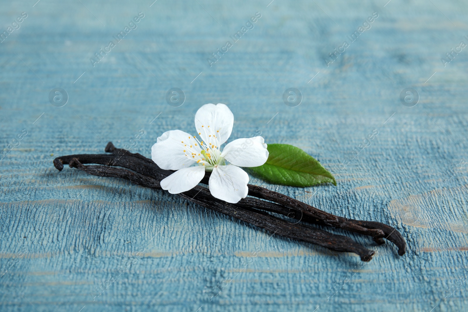 Photo of Aromatic vanilla sticks and flower on wooden background