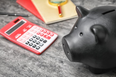 Photo of Black piggy bank and calculator on table