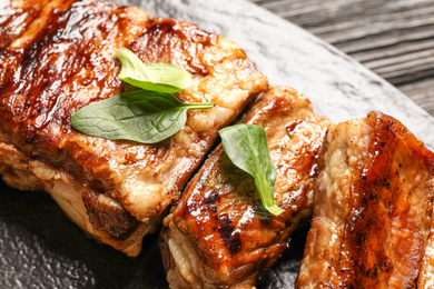 Photo of Delicious grilled ribs with spinach on table, closeup