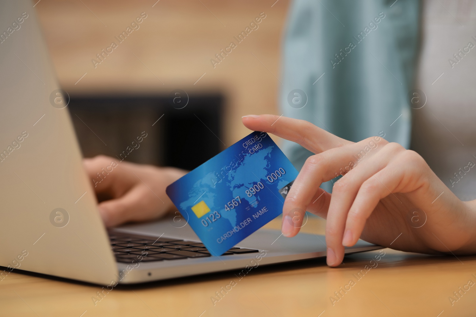 Photo of Woman with credit card using laptop for online shopping at wooden table, closeup