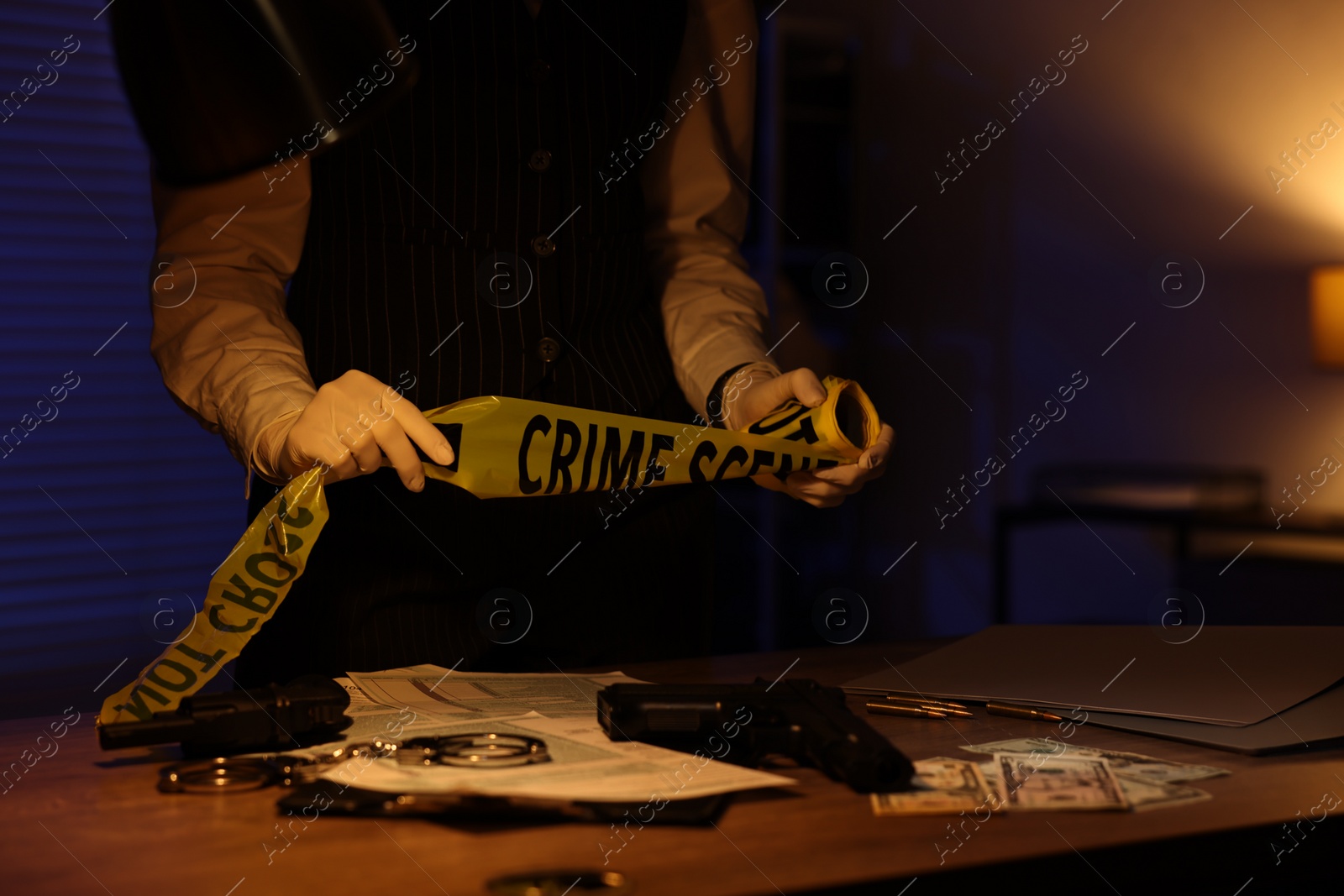 Photo of Professional detective with yellow crime scene tape in office at night, closeup