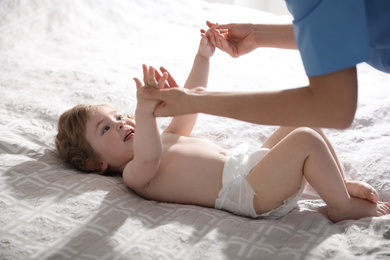 Photo of Orthopedist examining cute little baby on bed