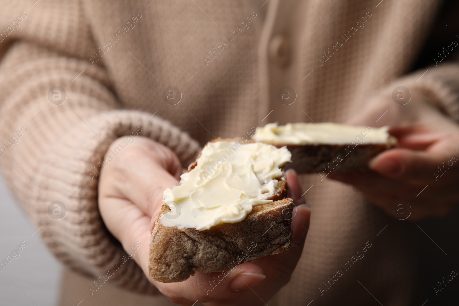 Photo of Woman holding slices of bread with butter, closeup