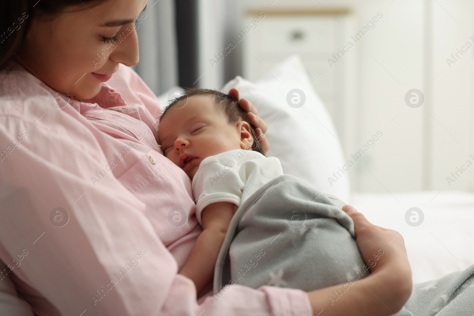 Photo of Mother with her sleeping newborn baby in bed at home