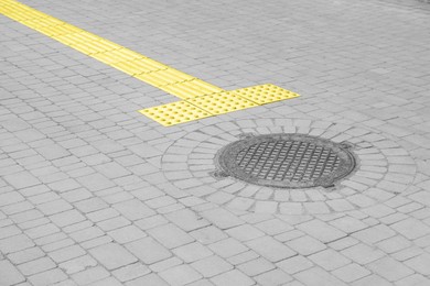 Metal sewer hatch on street tiles outdoors, space for text