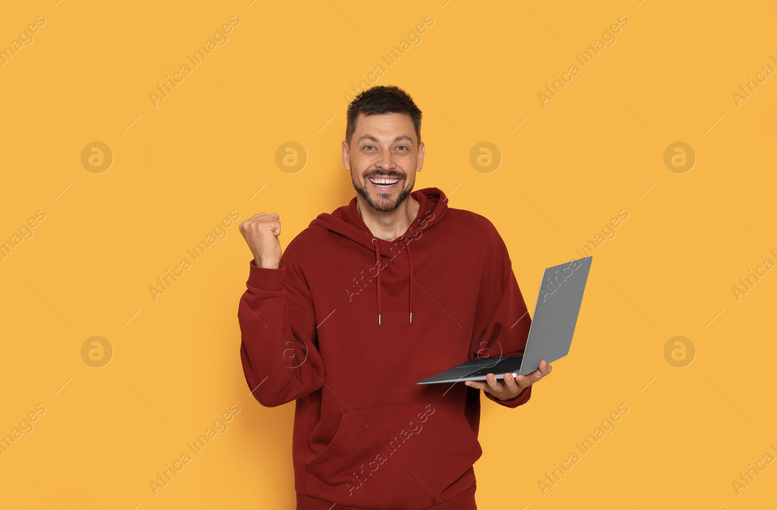 Photo of Happy man with laptop on orange background