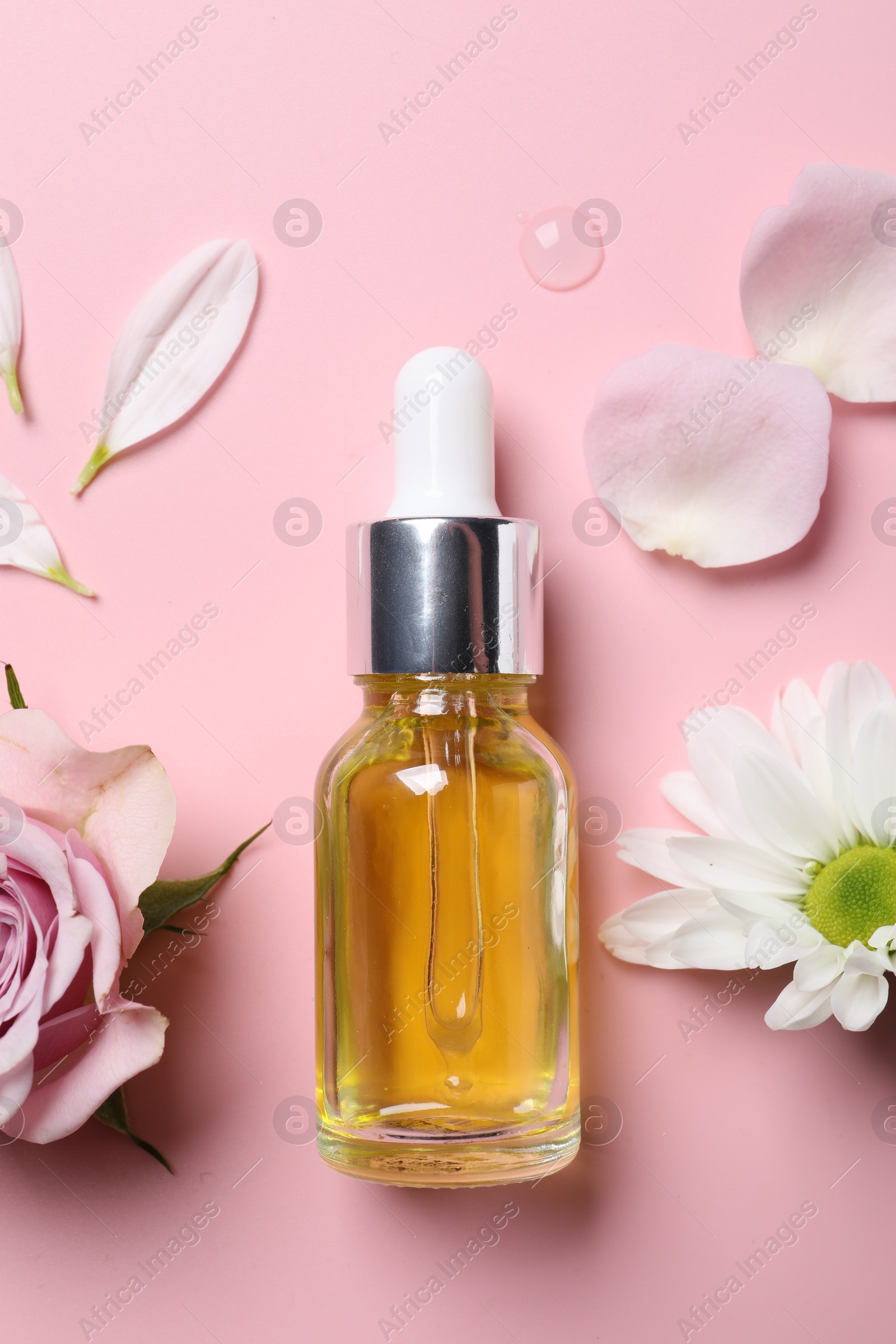 Photo of Bottle of cosmetic serum and beautiful flowers on pink background, flat lay