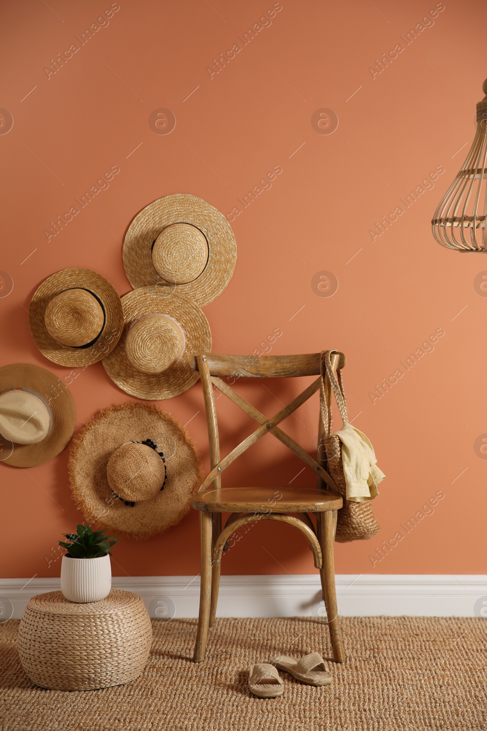 Photo of Wooden chair with bag and straw hats on brown wall. Interior design