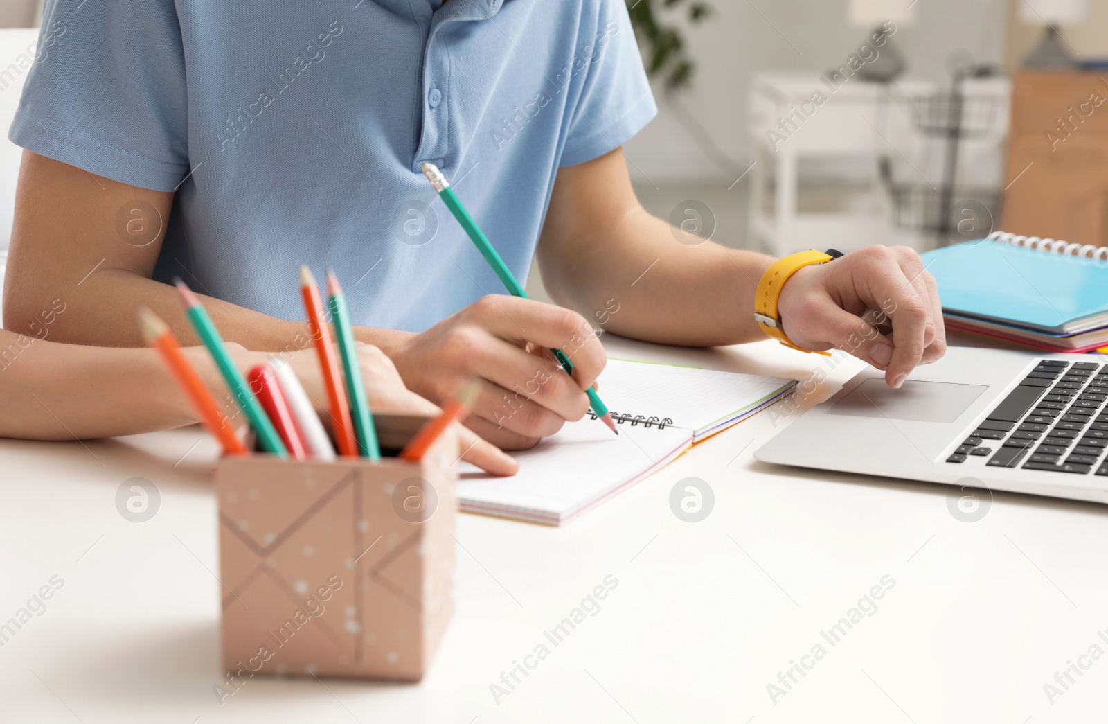 Photo of Mother helping her teenager son with homework at desk, closeup