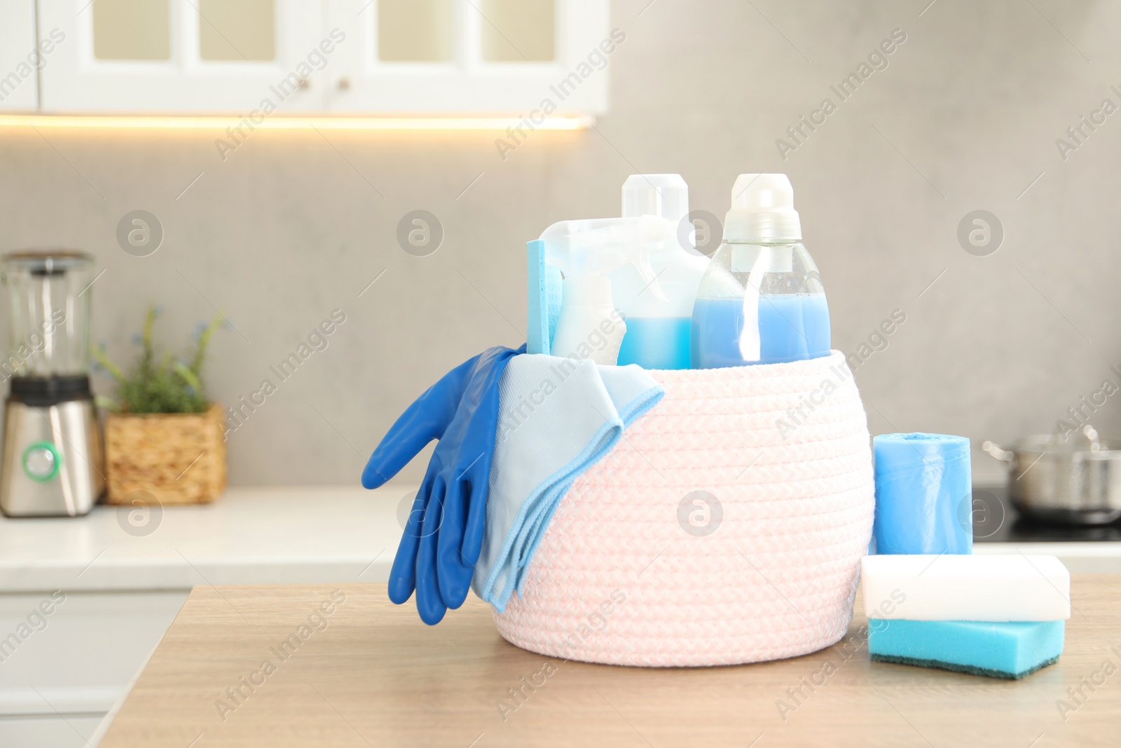 Photo of Different cleaning supplies in basket on table. Space for text