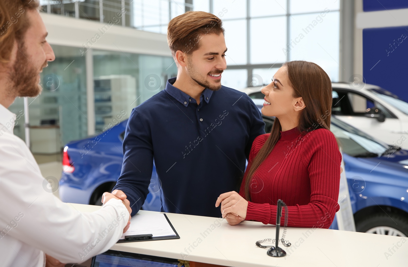 Photo of Car salesman and young couple in dealership