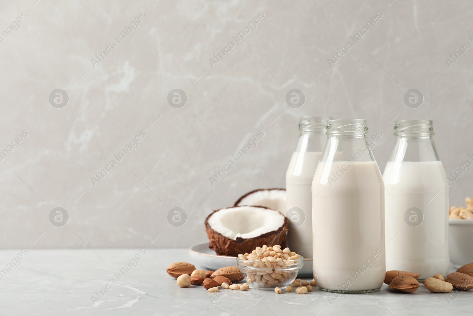 Photo of Different nut milks on light grey marble table. Space for text