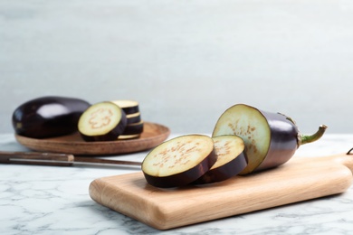 Photo of Wooden board with ripe eggplants on table