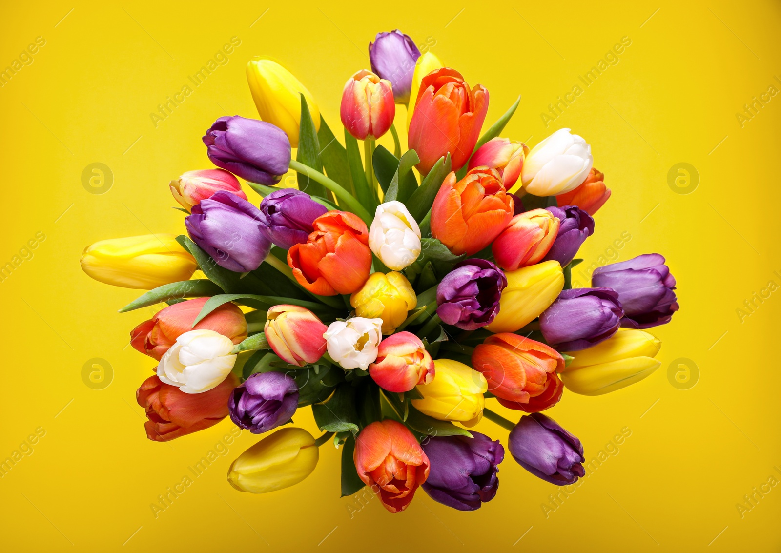 Photo of Bouquet of beautiful colorful tulips on yellow background, top view