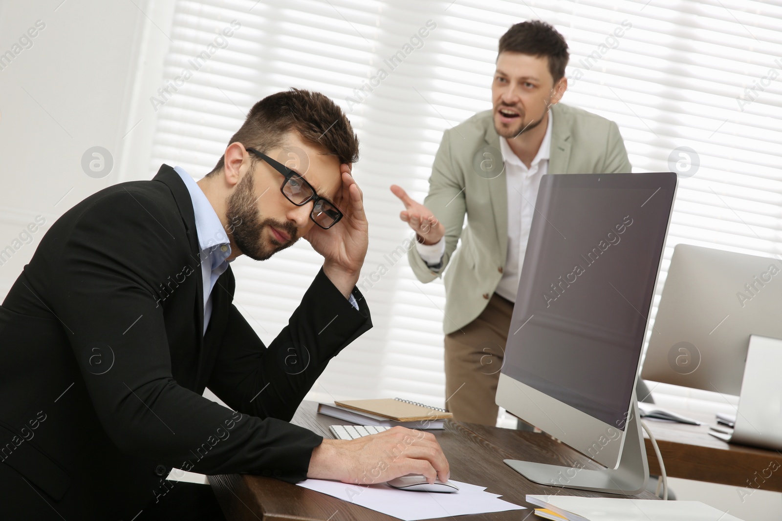 Photo of Boss screaming at employee in office. Toxic work environment