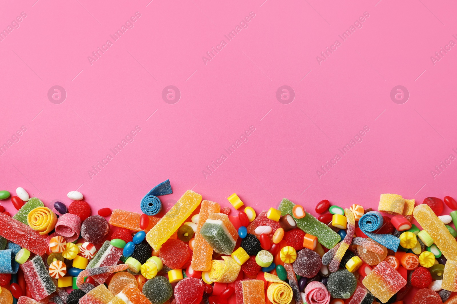 Photo of Flat lay composition with delicious colorful candies and space for text on color background