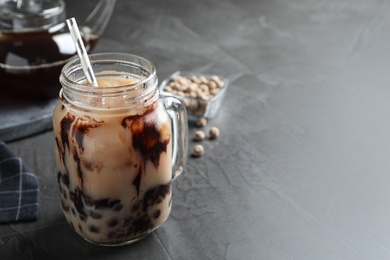 Photo of Tasty brown milk bubble tea on grey table, closeup. Space for text