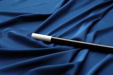 Photo of Beautiful black magic wand on blue fabric