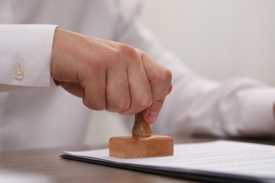 Photo of Man stamping document at table, closeup view