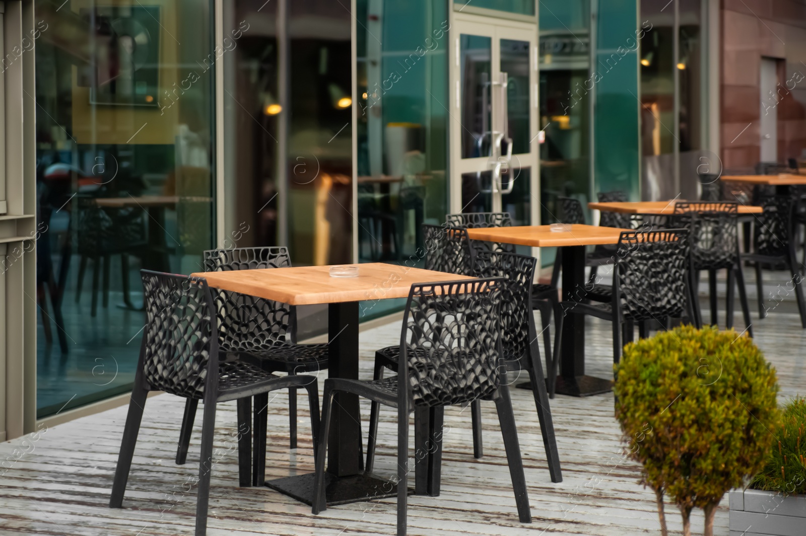 Photo of Chairs and tables on wooden terrace near cafe